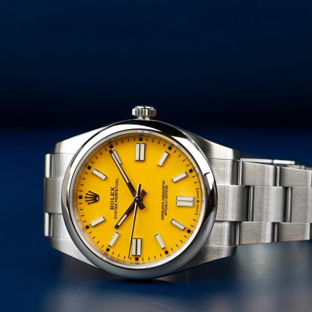 Reloj de carátula amarilla y brazalete de acero sobre un fondo azul oscuro